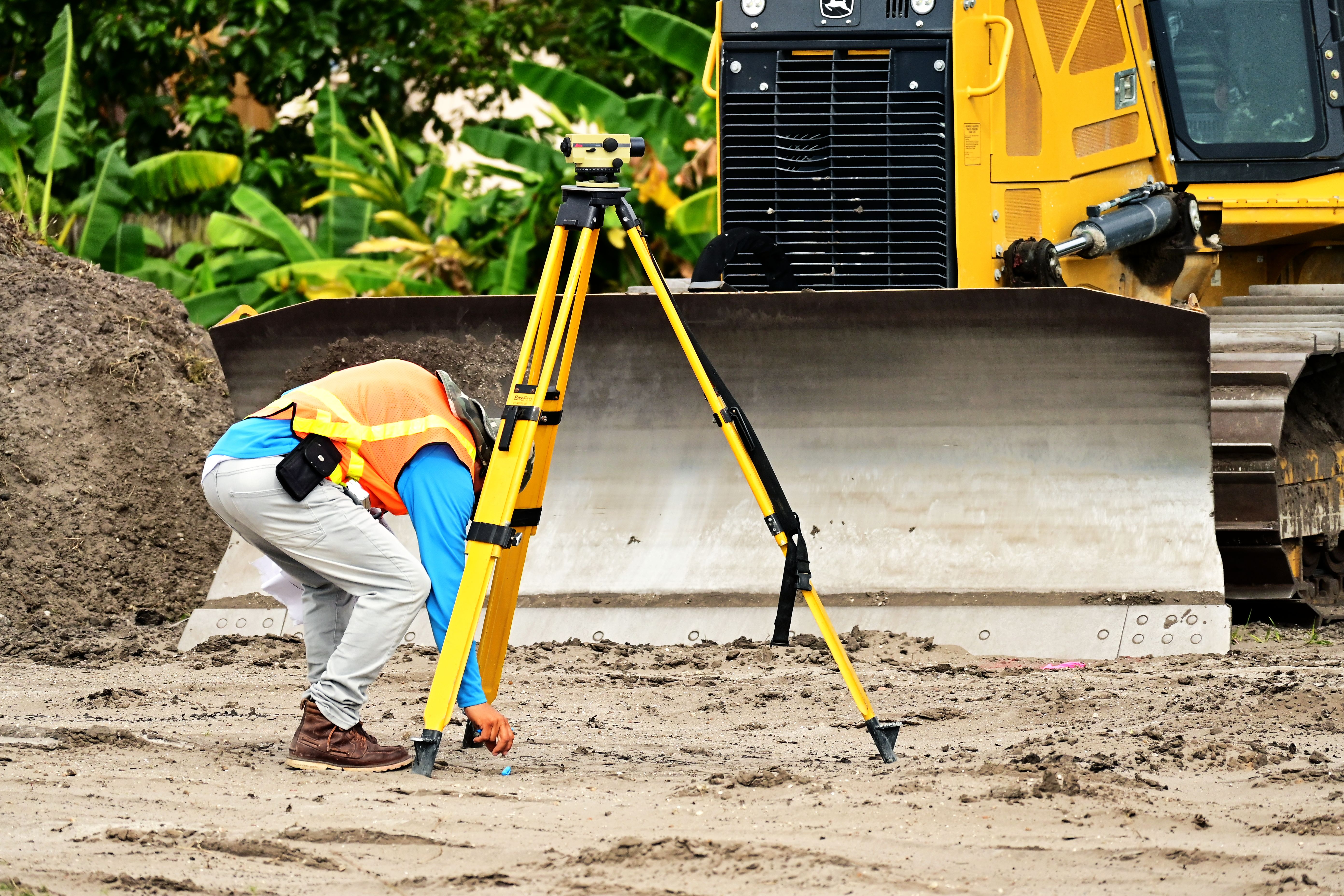 Surveyor setting the tripod over a boundary point on cleared ground